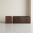 twowooden slat planters in light beige, dark brown, reddish-brown, and medium-to-dark brown, arranged on a light gray floor against a textured off-white wall.